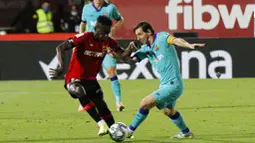Striker Barcelona, Lionel Messi, berusaha melewati pemain Mallorca, Iddrisu Mohamed, pada laga La Liga di Estadio de Son Moix, Minggu (14/6/2020). Barcelona menang dengan skor 4-0. (AP/Francisco Ubilla)