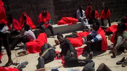 Sejumlah imigran beristirahat setelah perahu karet yang membawa 135 orang diselamatkan oleh penjaga pantai Spanyol di Mediterania di pelabuhan Tarifa, Spanyol (24/7). (AFP Photo/Jorge Guerrero)