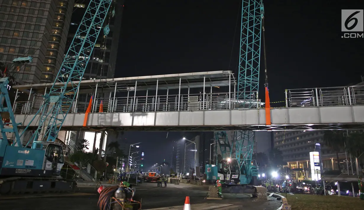 Petugas menggunakan alat berat merobohkan Jembatan Penyebrangan Orang (JPO) di Kawasan Bundaran HI, Jakarta, Senin (30/7/2018) malam. Pembongkaran JPO ini juga terkait upaya mempercantik ibu kota jelang Asian games 2018. (Liputan6.com/Herman Zakharia)