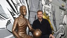 Bintang Timnas Inggris, Harry Kane, berpose di sebelah patung dirinya yang berada di The Peter May Centre, London, Senin (18/11/2024) waktu setempat. (Zac Goodwin/PA via AP)