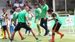 Mantan striker Timnas Indonesia, Kurniawan Dwi Yulianto, beradu skill dengan seorang anak pada acara Milo Football Clinic di Lapangan Sepak Bola Pertamina, Simprug, Jakarta, Minggu (24/4/2016). (Bola.com/Nicklas Hanoatubun)