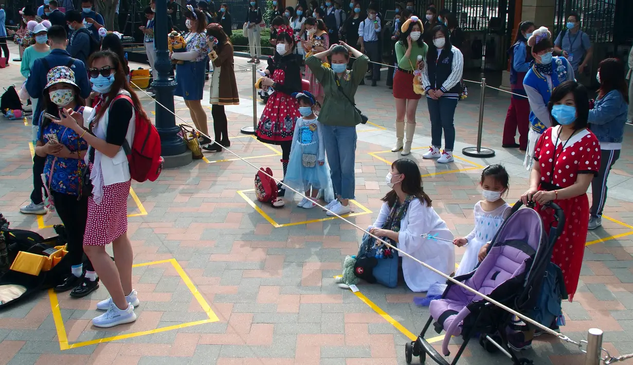 <p>Wisatawan mengenakan masker dan menerapkan physicl distancing saat menunggu untuk memasuki taman hiburan Disneyland, Shanghai, China, Senin (11/5/2020). Selain membatasi jumlah pengunjung, wisatawan maupun karyawan juga harus melewati pemeriksaan suhu tubuh. (AP Photo/Sam McNeil)</p>