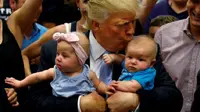 Donald Trump berfoto bersama bayi dalam sebuah kampanye (Reuters)