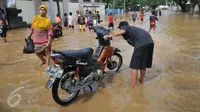 Warga memanfaatkan air banjir yang merendam kawasan Tebet, Jakarta, untuk mencuci motor, Selasa (8/3/2016). Banjir akibat luapan Kali Ciliwung tersebut merendam kawasan itu sejak pagi tadi. (Liputan6.com/Gempur M Surya)