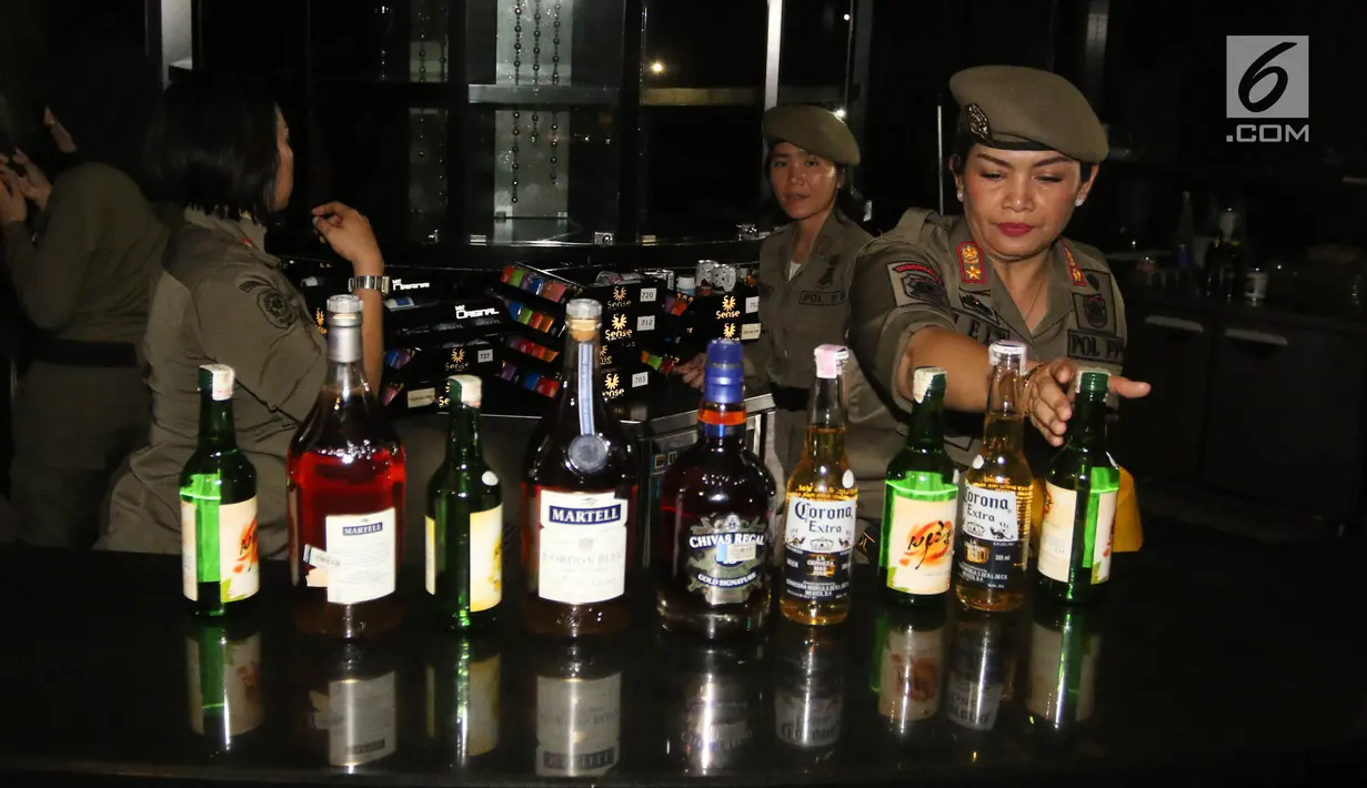 Petugas Satpol PP wanita mengamankan sejumlah botol minuman keras di Sense Karaoke, Mangga Dua Square, Jakarta, Kamis (19/4). Pemprov DKI Jakarta resmi menutup Sense Karaoke karena melanggar peraturan. (Liputan6.com/Arya Manggala)