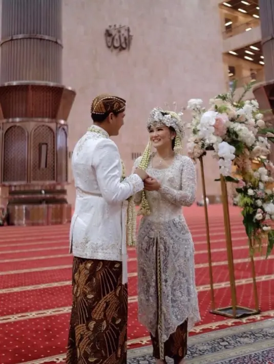 Kemudian di akad nikah, Clara memilih kebaya adat Sunda warna putih, senada dengan beskap Qausar. Mahkota Siger warna perak menghiasi kepalanya. (Instagram/myrnamyura).