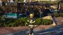 Seorang petugas pemadam kebakaran berjalan melewati sebuah bus yang meledak di Yerusalem, Israel, Senin (18/4). Menurut pejabat polisi peristiwa yang melukai 16 orang itu adalah serangan yang disengaja. (Menahem KAHANA / AFP)