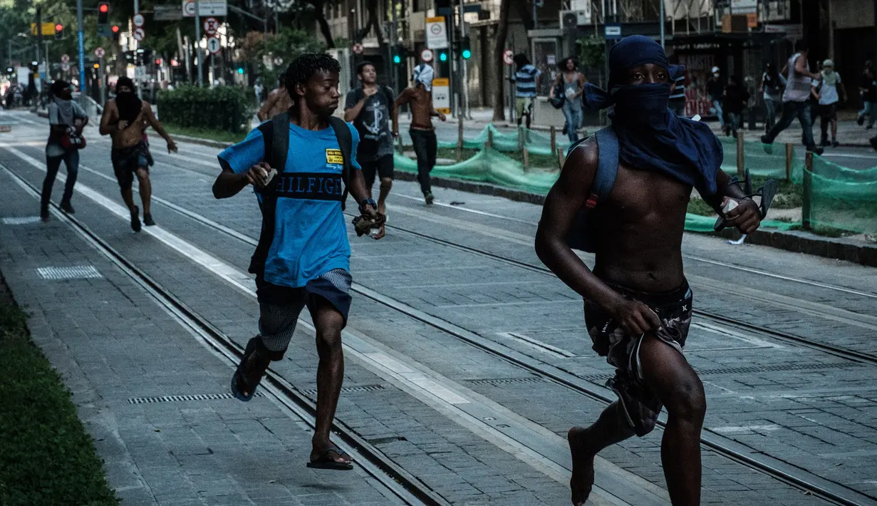 Sejumlah pengunjuk rasa berlari saat bentrok dengan polisi selama protes rencana pembatasan belanja publik di Rio de Janeiro, Brasil, (9/2). (AFP Photo / Yasuyoshi Chiba)