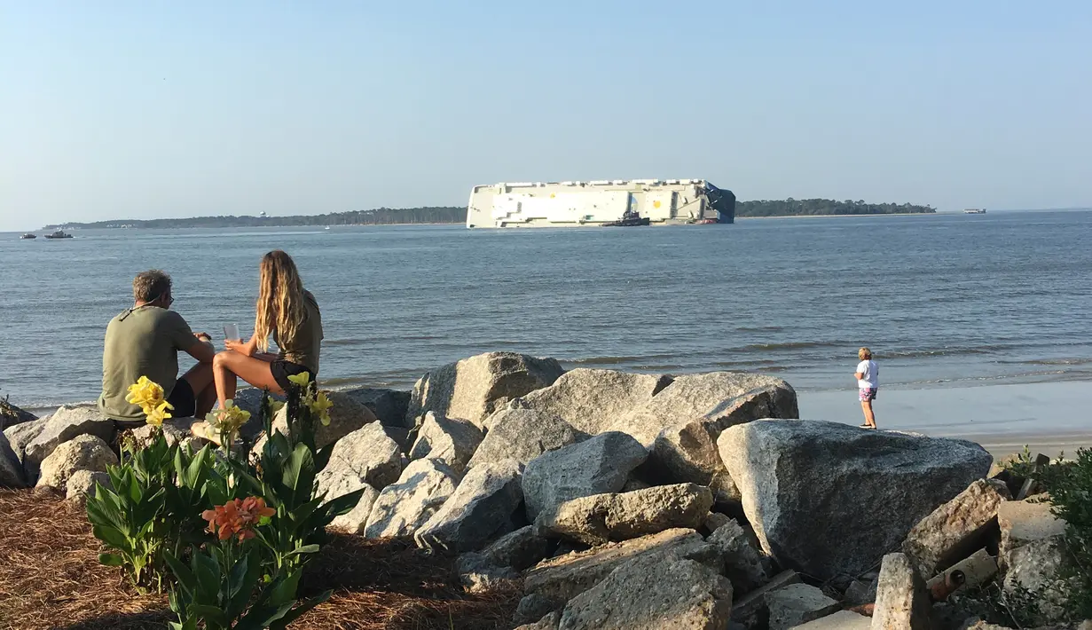 Warga menyaksikan kapal kargo Golden Ray yang terbalik di lepas pantai negara bagian Georgia, Amerika Serikat, Minggu (8/9/2019). Korban selamat terdiri dari enam warga Korsel, 13 Filipina, dan satu pilot maritim asal Amerika Serikat. (Tara Jones via AP)