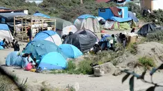 Imigran gelap berjalan di dekat puluhan tenda yang didirikan di sebuah kamp sementara di sekitar pelabuhan Calais, Prancis, Minggu (2/8/2015). Sebelumnya, ratusan imigran memaksa masuk Prancis melalui Terowongan Channel. (AFP PHOTO/FRANCOIS LO PRESTI)