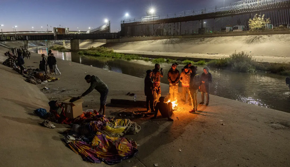 Migran menghabiskan malam di luar, dekat pagar perbatasan AS-Meksiko sambil menunggu pengajuan klaim suaka di El Paso, Texas, di Ciudad Juarez, Meksiko, Rabu (21/12/2022). Judul 42 memungkinkan pemerintah mengirim migran dari negara tertentu, termasuk Venezuela, kembali ke Meksiko tanpa kesempatan untuk mencari suaka. (JOHN MOORE / GETTY IMAGES NORTH AMERICA / Getty Images via AFP)