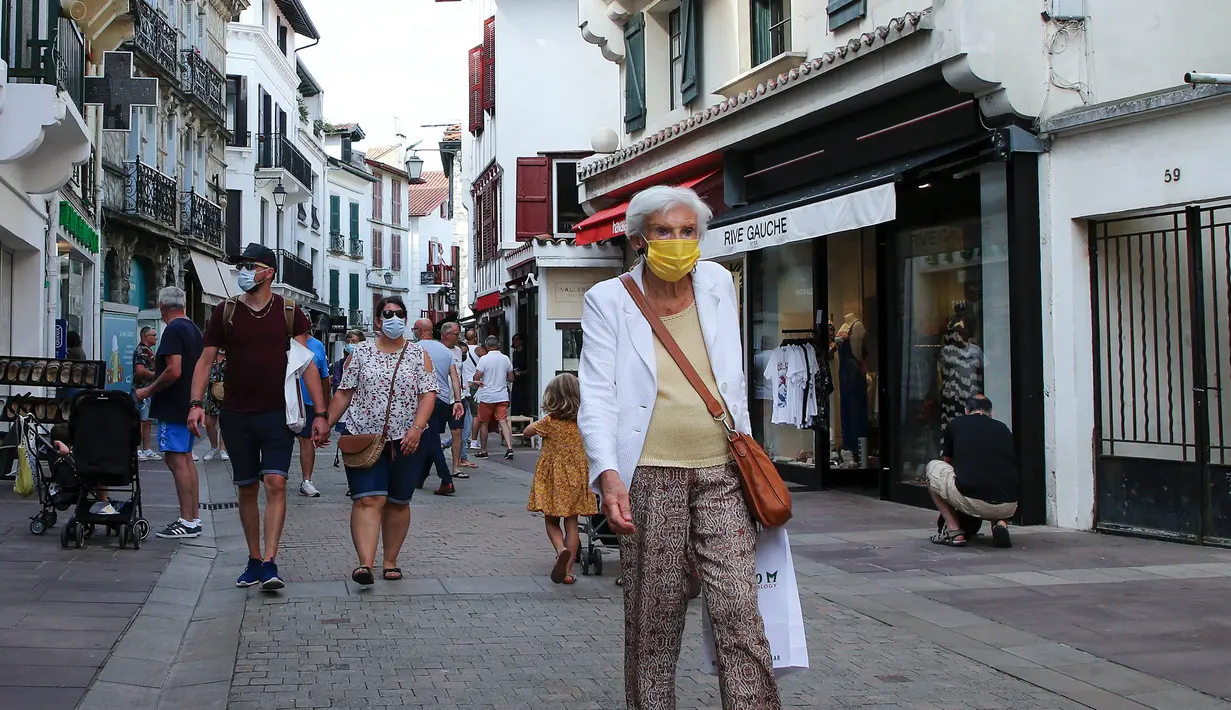 Orang-orang dengan masker berjalan di jalur pejalan kaki di Saint Jean de Luz, Prancis barat daya, Selasa (27/7/2021). Otoritas setempat di Prancis memberlakukan kembali mandat masker dan pembatasan COVID-19 lainnya karena penyebaran varian delta menyebabkan rawat inap meningkat lagi. (AP/Bob Edme)