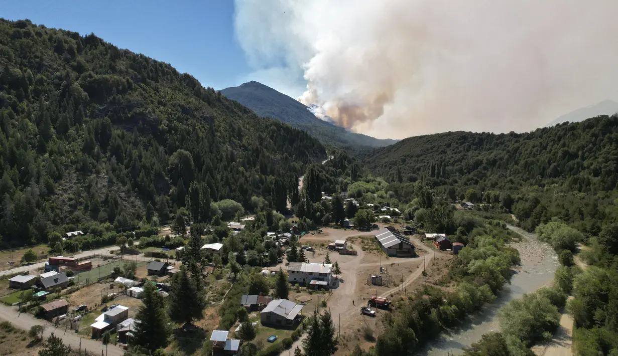 Asap mengepul dari kebakaran hutan besar terlihat dari Paraje Villegas, Provinsi Rio Negro, 70 km selatan Bariloche, Argentina (24/12/2021). Sekitar 250 petugas pemadam kebakaran dan karyawan taman nasional berjuang melawan api yang telah menghancurkan ribuan hektar lahan hutan. (AFP/ Francisco Ramo