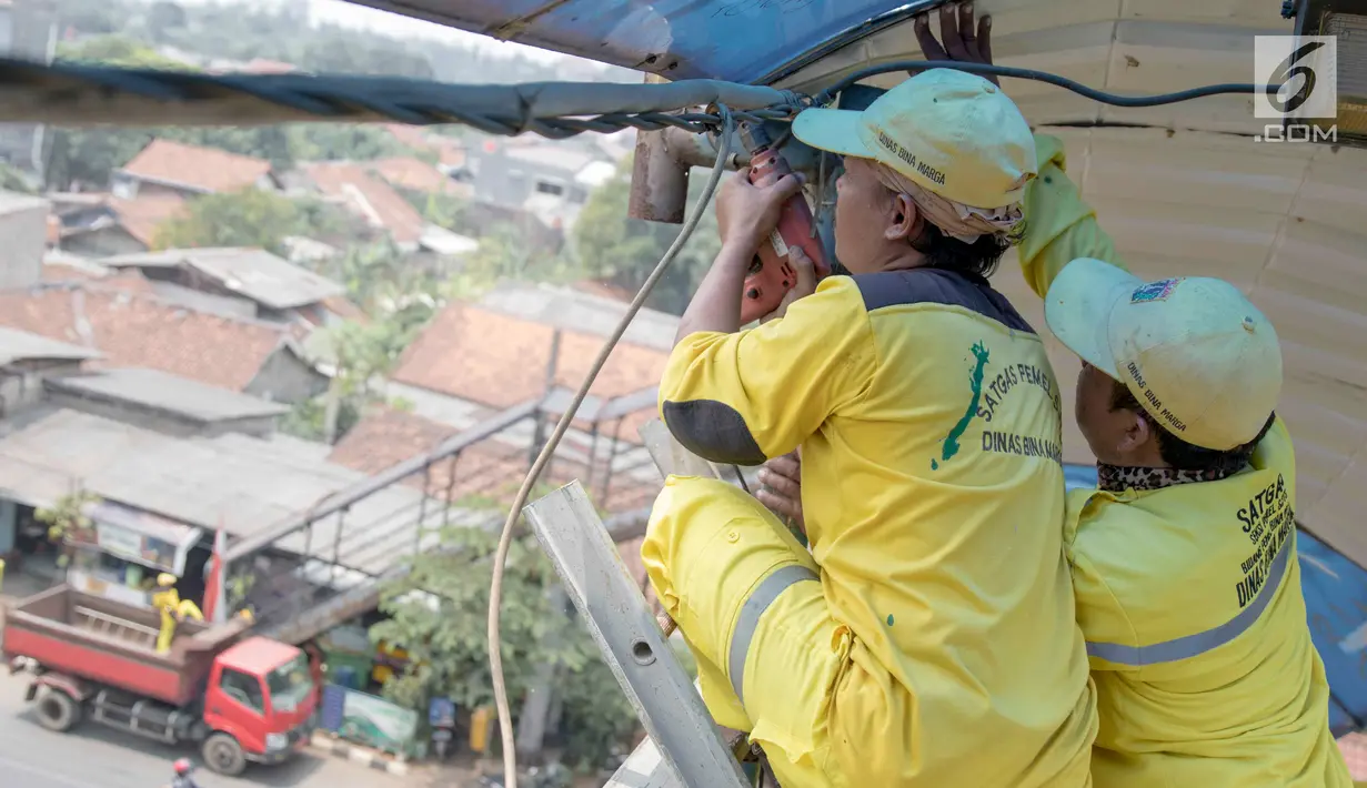 Petugas memerbaiki atap JPO di sekitar kawasan Lenteng Agung, Jakarta, Selasa (28/8). Hal itu dilakukan guna memberikan kenyamanan bagi pengguna JPO, mengingat banyak bagian dari JPO tersebut yang telah keropos dan rusak. (Liputan6.com/Immanuel Antonius)