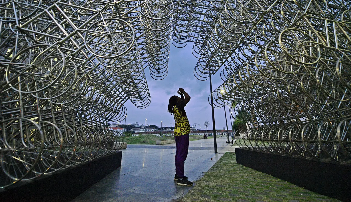 Seorang pria mengambil gambar instalasi seni seniman China Ai Weiwei yang berjudul 'Forever Cycles' di Rio de Janeiro, Brasil, Senin (19/8/2019). Instalasi Ai Weiwei ini akan dibuka pada 21 Agustus 2019. (CARL DE SOUZA/AFP)