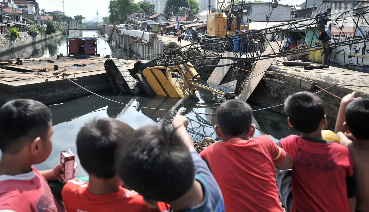 Anak-anak menyaksikan petugas mengevakuasi crane yang jatuh di kawasan Kemayoran, Jakarta, Kamis (6/12). Crane yang jatuh tersebut jatuh hingga menimpa rumah warga dan menyebabkan tiga orang luka-luka. (Merdeka.com/Iqbal S. Nugroho)