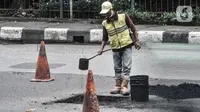 Petugas dari Dinas Bina Marga mengerjakan perbaikan jalan berlubang di Jalan DI Panjaitan, Cawang, Jakarta, Senin (25/1/2021). Perbaikan jalan rusak dan berlubang akibat sering tergenang banjir di kawasan tersebut untuk mengantisipasi terjadinya kecelakaan pengendara. (merdeka.com/Iqbal S Nugroho)
