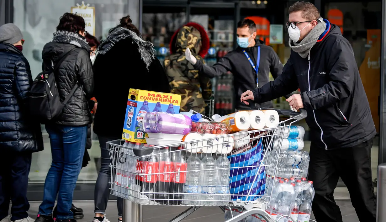 Orang-orang mengenakan masker antre di luar sebuah supermarket di Casalpusterlengo, Minggu (23/2/2020). Mereka memborong perlengkapan dan bahan-bahan kebutuhan pokok karena tak mau keluar rumah menyusul dua warga Italia yang meninggal karena Virus Corona COVID-19. (Claudio Furlan/Lapresse via AP)