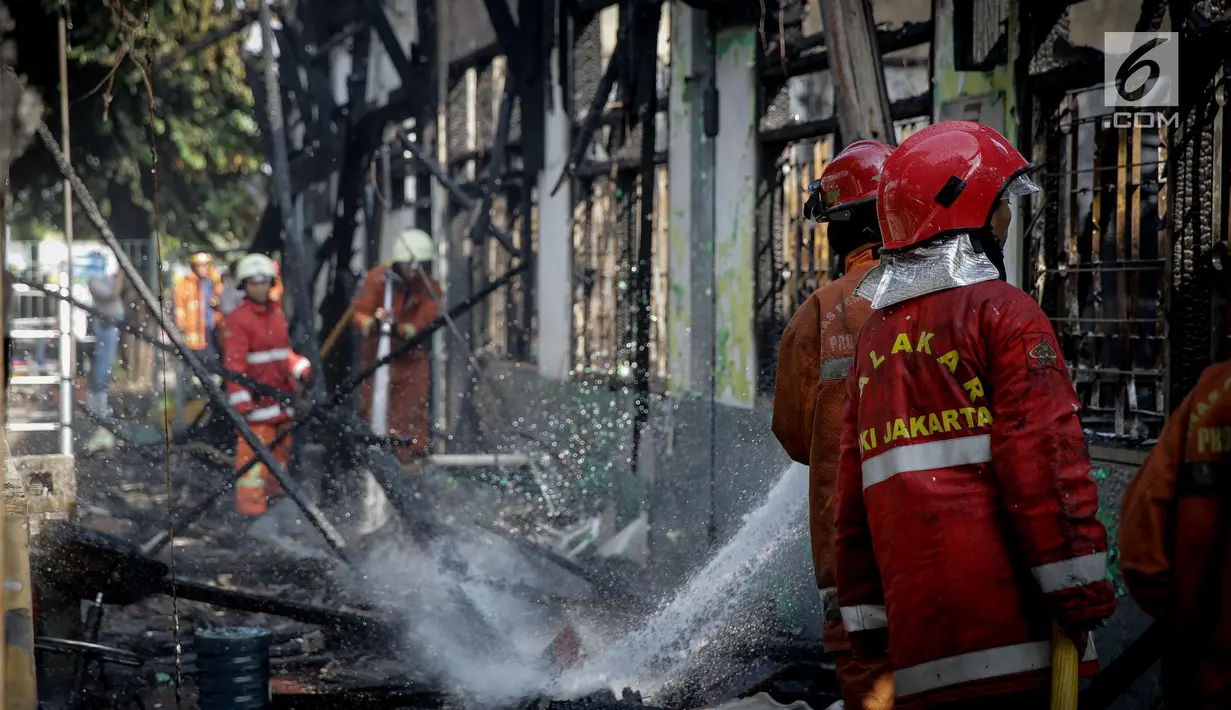 Petugas melakukan pendinginan pada Stasiun Klender, Jakarta Timur, yang terbakar, Jumat (19/5). Akibat kebakaran, operasional naik-turun penumpang kereta api listrik (KRL) di stasiun itu dihentikan untuk sementara waktu. (Liputan6.com/Faizal Fanani)