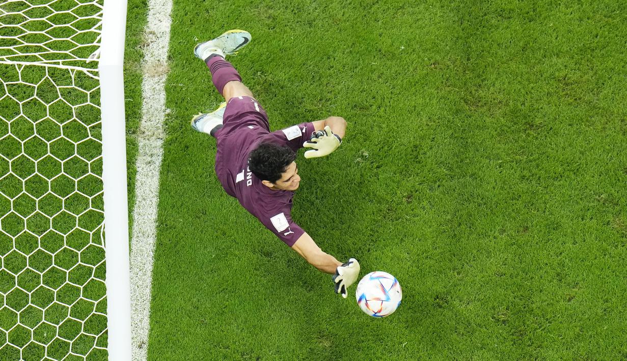 Kiper Maroko, Yassine Bounou, menghalau bola saat babak adu penalti melawan Spanyol pada laga 16 besar Piala Dunia 2022 di Stadion Education City, Selasa (6/12/2022). (AP/Petr David Josek)