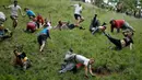 Sejumlah peserta saling berjatuhan saat mengejar gulungan keju yang diturunkan dari atas bukit Cooper Hill dalam kompetisi tahunan, Cheese Rolling di Brockworth, Gloucestershire, Inggris, 30 Mei 2016. (Adrian DENNIS/AFP)