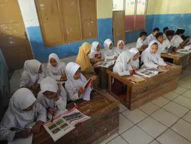 Murid-murid kelas V melakukan kegiatan belajar pada meja yang diubah menjadi kursi dan tempat belajar di SDN Kertajaya 2, Rumpin, Bogor (22/7/2019). Sudah lebih dari tiga tahun mereka belajar  pada fasilitas yang minim. (merdeka.com/Arie Basuki)
