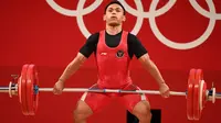 Lifter andalan Indonesia, Eko Yuli Irawan berusaha mengangkat beban saat bertanding dalam kelas 61kg putra Grup A cabor angkat besi Olimpiade Tokyo 2020 di Tokyo International Forum, Minggu (25/7/2021). Eko Yuli meraih medali perak dengan total angkatan 302 kg. (Vincenzo PINTO / AFP)