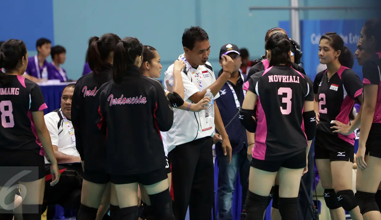 Pelatih tim voli putri Indonesia, Muhamad Ansori (kaos putih) memberikan arahan saat time out semifinal voli putri SEA Games ke-28 di OCBC Arena, Singapura, Minggu (14/6/2015). Pevoli Indonesia kalah 1-3 dari Thailand. (Liputan6.com/Helmi Fithriansyah)