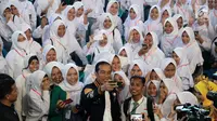 Presiden Joko Widodo atau Jokowi berswafoto dengan siswa SMA penerima Kartu Indonesia Pintar (KIP) di Gorontalo, Jumat (1/3). Tahun 2019 Provinsi Gorontalo mendapatkan jatah 80.502 KIP. (Liputan6.com/Arfandi Ibrahim)