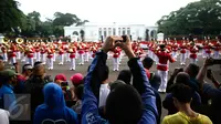 Warga mengabadikan gambar prosesi serah terima pergantian pasukan jaga Istana Kepresiden di depan Istana Merdeka, Minggu (28/8). Ini merupakan pelaksanaan seremoni pergantian pasukan jaga istana untuk yang kedua kalinya (Liputan6.com/Faizal Fanani)