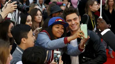 Aktor Zac Efron (kanan) berfoto selfie dengan para penggemarnya saat menghadiri pemutaran perdana film 'We Are Your Friends' di Brixton Oval, London, Inggris. Selasa (11/8/2015). (REUTERS/Luke MacGregor)