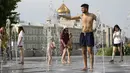 Seorang pria mengisi botol di air mancur sebuah taman di sebelah tanggul Sungai Moskow, di Moskow, Rusia, Rabu (14/7/2021). Cuaca panas di Moskow berlanjut dengan suhu mencapai 34 derajat Celcius (93,2 Fahrenheit) dalam sehari. (AP Photo/Pavel Golovkin)