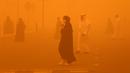 <p>Pejalan kaki menyeberang jalan di tengah badai debu parah di Kota Kuwait pada 23 Mei 2022. Badai pasir telah melanda Timur Tengah dalam beberapa hari terakhir, dan menjadi fenomena yang para ahli peringatkan dapat berkembang luas karena perubahan iklim. (Yasser Al-Zayyat / AFP)</p>