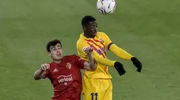 Penyerang Barcelona, Ousmane Dembele berebut bola udara dengan bek Osasuna, Manu Sanchez pada pertandingan lanjutan La Liga Spanyol di stadion El Sadar di Pamplona, Spanyol, Minggu (7/3/2021). Dengan kemenangan ini, Barcelona mengantongi 56 poin dari 26 pertandingan. (AP Photo/Alvaro Barrientos)