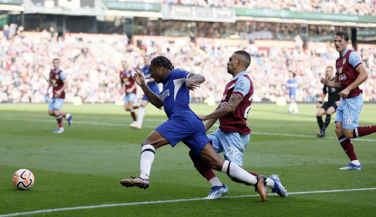Pemain Chelsea, Raheem Sterling, terjatuh saat berusaha melewati pemain Burnley, Vitinho, pada laga pekan ke-8 Premier League 2023/2024 di Stadion Turf Moor, Sabtu, (7/10/2023). Pemain asal Inggris itu tampil luar biasa. Dia terlibat dalam semua gol The Blues di pertandingan tersebut. (Richard Sellers/PA via AP)
