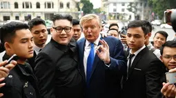 Peniru pemimpin Korut Kim Jong-un, Howard X dan peniru Presiden AS Donald Trump, Dennis Alan dikelilingi wartawan di luar Gedung Opera, Vietnam  (22/2). Aksi tersebut dilakukan menjelang KTT Trump-Kim mendatang di Hanoi. (AFP Photo/Manan Vatsyayana)