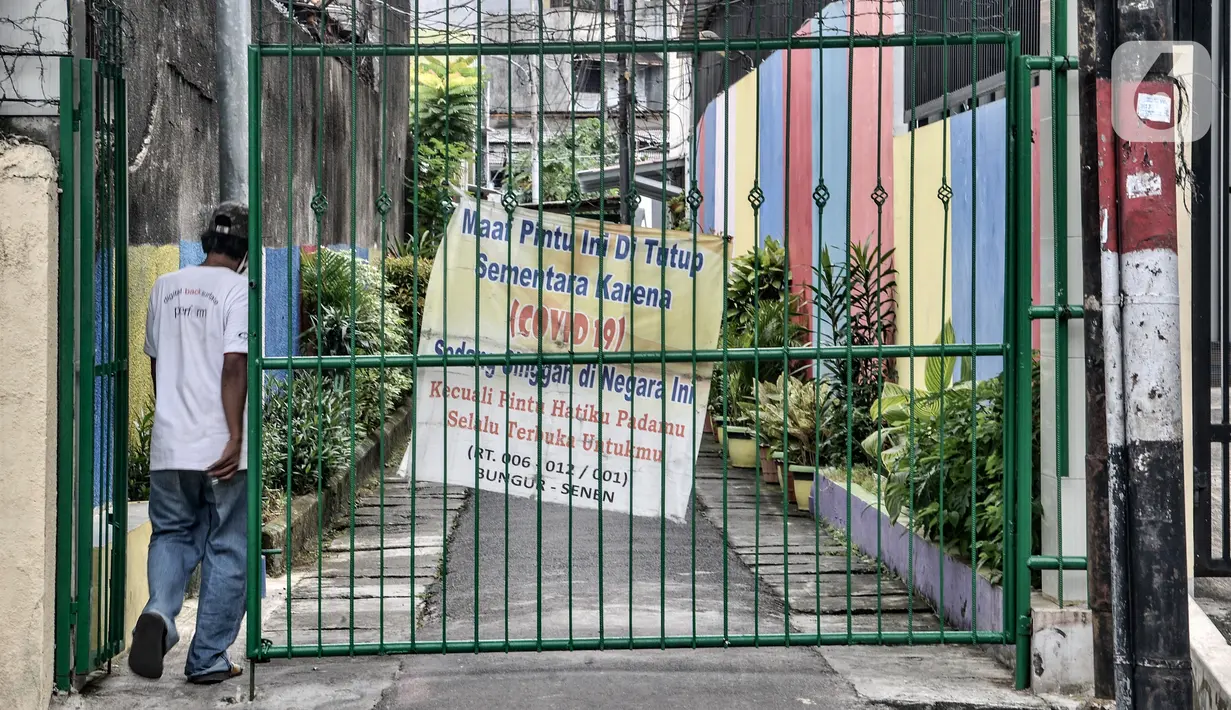 Warga melintasi gapura yang ditutup di wilayah zona merah COVID-19 di RW 01 Kelurahan Bungur, Jakarta, Rabu (10/2/2021). Data yang tercatat di laman corona.jakarta.go.id menyebut zona merah di Jakarta Selatan sebanyak 41 RW dan Jakarta Pusat 16 RW. (merdeka.com/Iqbal S. Nugroho)