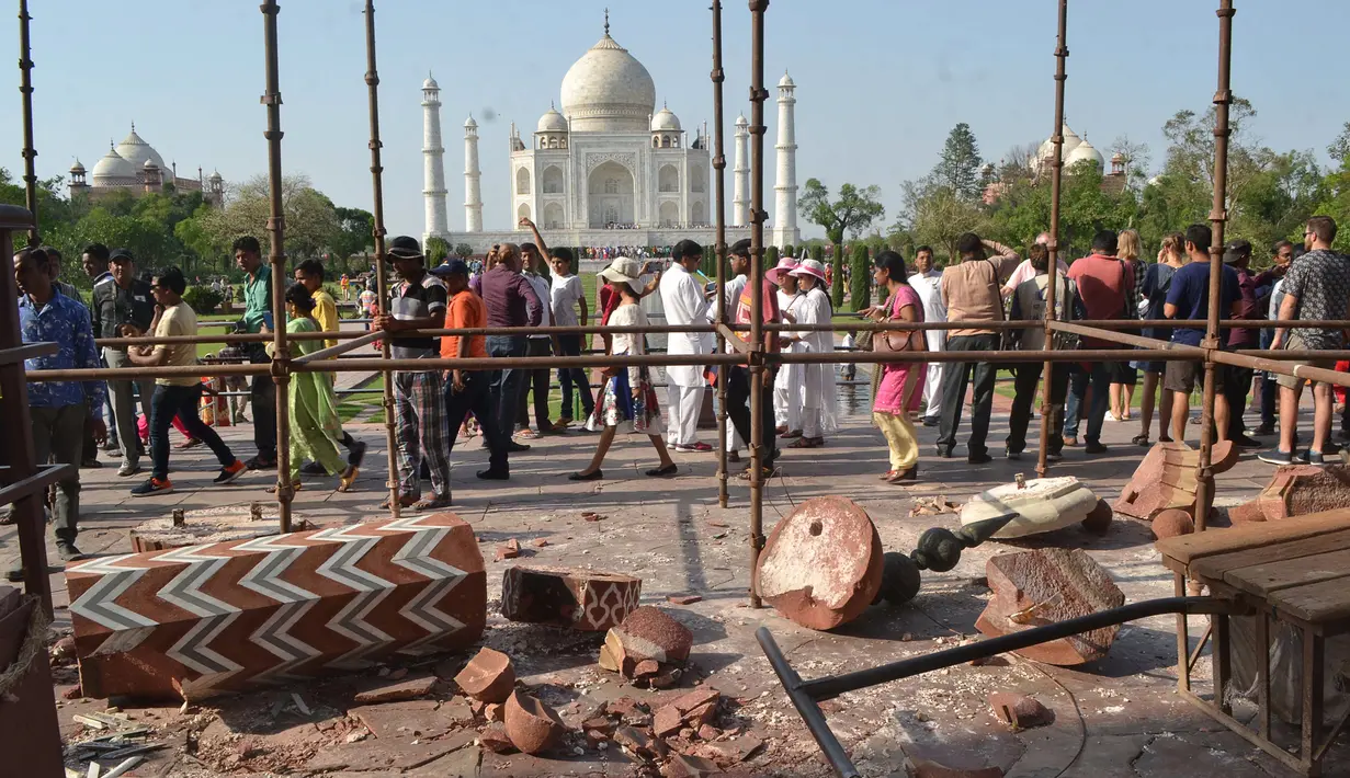 Wisatawan berkumpul di sekitar royal gate atau gerbang kerajaan setelah pilar Taj Mahal runtuh diterpa angin kencang di Agra, India, Kamis (12/4). Dua pilar Taj Mahal yang roboh diterpa angin kencang itu terdapat di gerbang masuk yang berbeda. (AFP Photo)