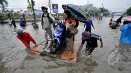 Pengendara motor saat menggunakan jasa gerobak untuk melintasi banjir di Jalan Gunung Sahari, Jakarta, Senin (6/2/2015). Jasa gerobak Mematok harga Rp. 30 ribu untuk membawa motor sedangkan untuk per orang hanya Rp. 10 ribu. (Liputan6.com/Faizal Fanani)