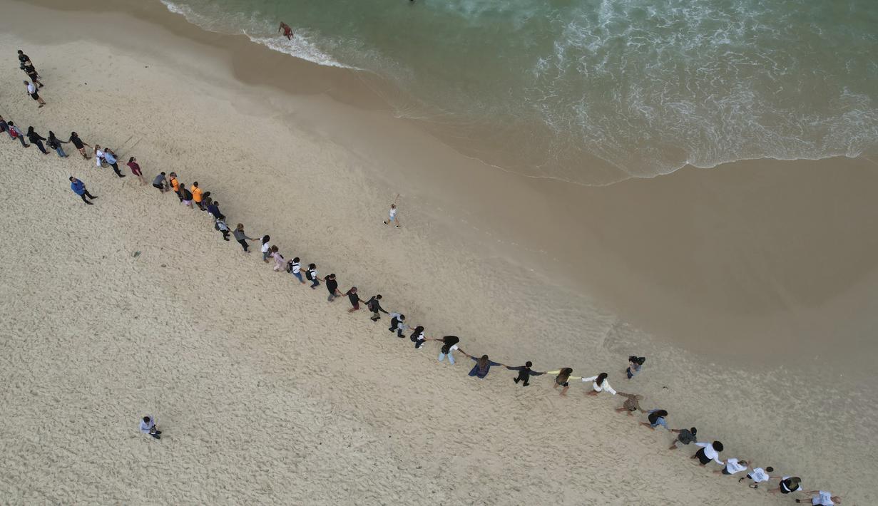 Orang-orang membuat garis di sepanjang pantai Copacabana pada Hari Laut Sedunia di Rio de Janeiro, Brasil, Rabu (8/9/2022). Organisasi Route Brasil menyerukan agar orang-orang berkumpul untuk acara yang diberi nama "Pelukan Itu," dan untuk memungut sampah di pantai, untuk menarik perhatian pada pencemaran laut. (AP Photo/Silvia Izquierdo)