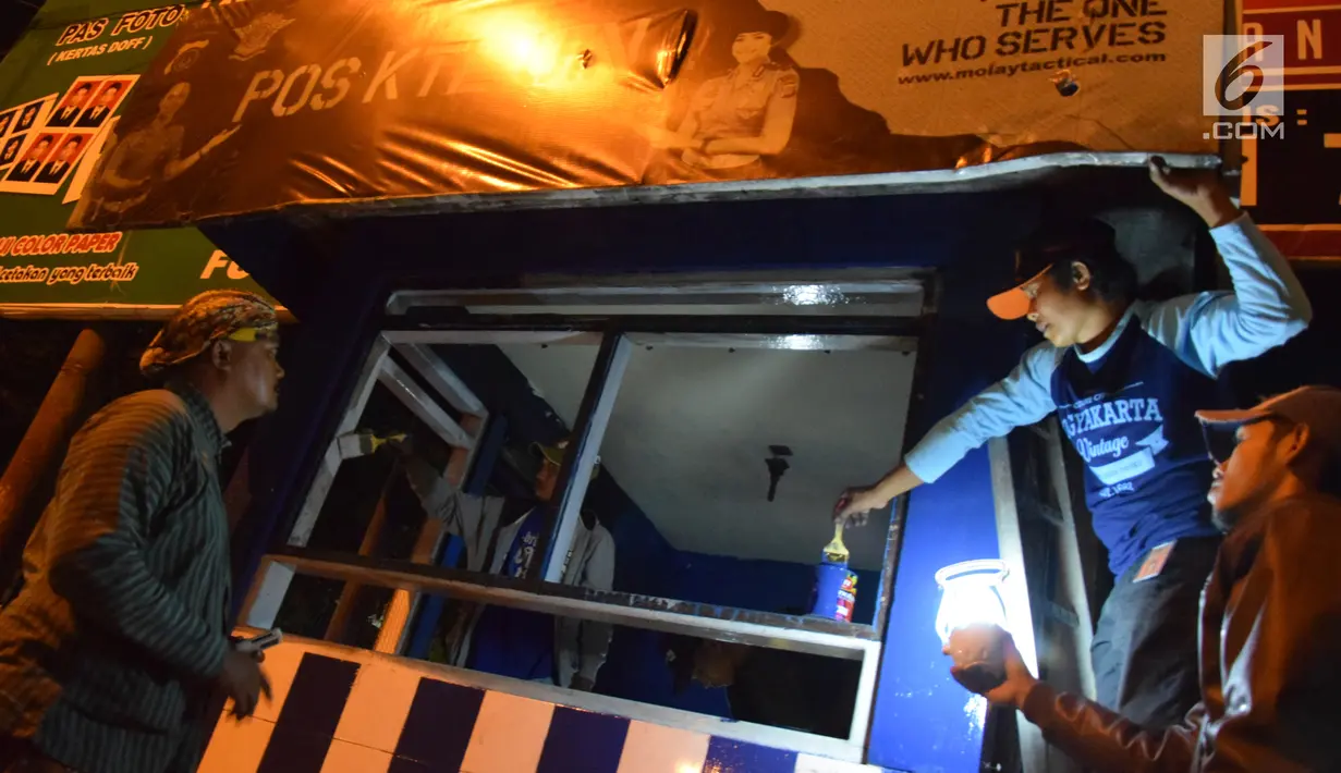 Petugas dan warga mengecat pos polisi yang sebelumnya dibakar massa saat peringatan Hari Buruh di Yogyakarta, Selasa (1/5) malam. Hari Buruh di Yogyakarta diwarnai aksi bakar pos polisi di pertigaan kampus UIN Sunan Kalijaga. (Liputan6.com/Gholib)