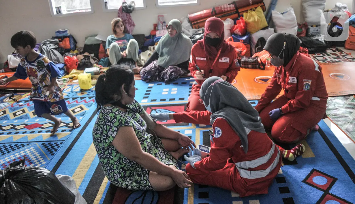Petugas Palang Merah Indonesia (PMI) memeriksa kesehatan warga korban kebakaran yang mengungsi di Kantor Kelurahan Jembatan Lima, Tambora, Jakarta Barat, Rabu (27/7/2022). Kebakaran yang terjadi pada Selasa (26/7/2022) dini hari tersebut sedikitnya menghanguskan 48 rumah di RT 04 dan 05, RW 08 Kelurahan Jembatan Lima dan memaksa 75 KK yang terdiri atas 300 jiwa kehilangan tempat tinggal. (merdeka.com/Iqbal S Nugroho)