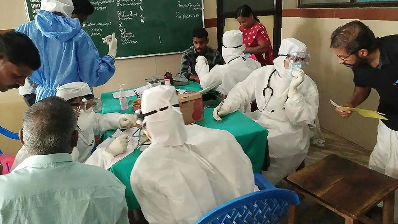 Petugas medis yang mengenakan pakaian pelindung sedang memeriksa pasien di rumah sakit Medical College di Kozhikode, India.