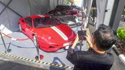 Pengunjung memfoto mobil mewah yang siap dilelang terbuka pada acara Badan Pemulihan Aset (BPA) Kejaksaan Agung Fair 2026 di Jakarta, Kamis (21/5/2026). (merdeka.com/Arie Basuki)