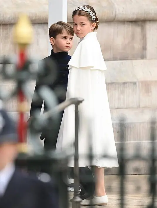 <p>Pada kesempatan ini, Princess Charlotte juga mengenakan dress rancangan Alexander McQueen dengan potongan bergaya cape putih. Sepatu flat shoes bergaya mary jane mempermanis tampilannya. Head pieces dengan aksen daun semakin menyempurnakan gayanya. [Foto: Instagram/ Kate_middleton_royal]</p>