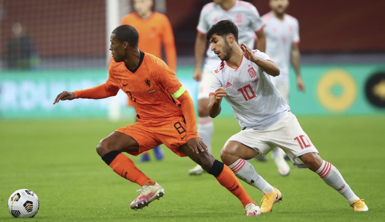 Penyerang Spanyol, Marco Asensio berebut bola dengan gelandang Belanda, Georginio Wijnaldum dalam laga persahabatan internasional di Johan Cruijff ArenA, Amsterdam, Kamis dinihari WIB (12/11/2020). Kedua tim bermain sama kuat 1-1. (Dean Mouhtaropoulos/Pool via AP)