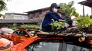 Seorang karyawan menanam sayuran di atap taksi yang terbengkalai di pool taksi di Bangkok, Thailand, Rabu (15/9/2021). Bagian atap hingga kap mobil yang tak lagi digunakan imbas pandemi COVID-19 itu dialihfungsi untuk menanam berbagai sayuran. (Jack TAYLOR/AFP)