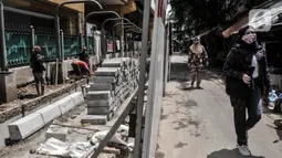 Pejalan kaki melintas di dekat pembangunan jalur pedestrian di Stasiun Gondangdia, Jakarta Pusat, Kamis (8/4/2021).  Stasiun Gondangdia pembangunannya juga akan dilakukan pembuatan area drop off dan pangkalan transportasi online maupun konvensional. (merdeka.com/Iqbal S. Nugroho)