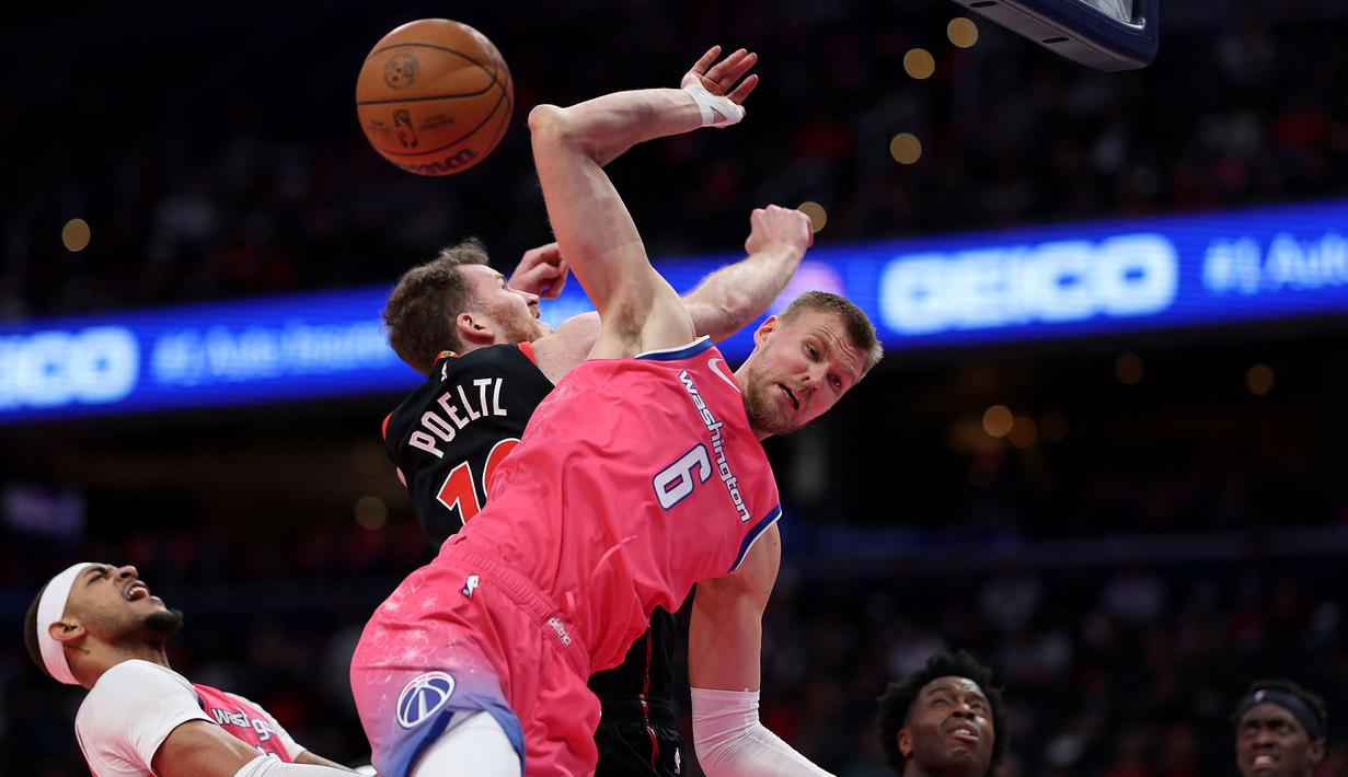 Pemain Washington Wizards, Kristaps Porzingis (kanan) berebut bola dengan pemain Toronto Raptors, Jakob Poeltl pada laga NBA 2023 di Capital One Arena, Washington, 2 Maret 2023. (AFP/Getty Images/Patrick Smith)