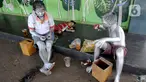 Seorang ibu menghitung uang hasil mengamennya sebagai "Manusia Silver " bersama sang anak di salah satu sudut toko di kawasan perempatan Gaplek, Pamulang, Tangerang Selatan, Sabtu (16/1/2021). Ibu tersebut mendapat penghasilan sekitar 50 ribu per hari sebagai Manusia Silver (merdeka.com/Arie Basuki)